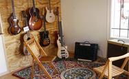 Chairs and amplifier in front of a wall of guitars